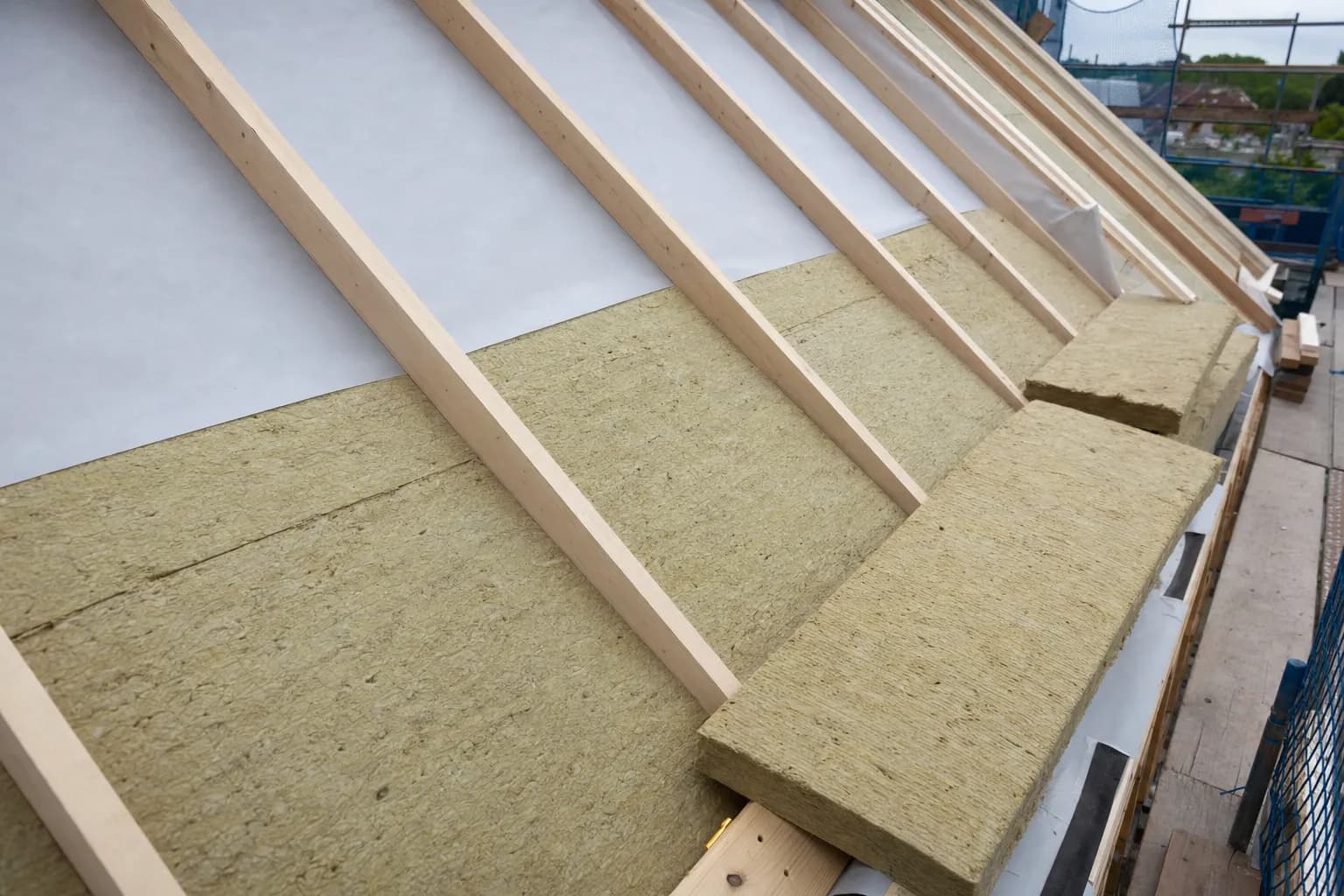 Blang Holzbau carpenter fitting insulation between the rafters of a timber roof truss